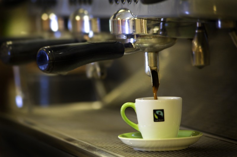 Aus einer Kaffeemaschine rinnt Kaffee in eine Kaffeetasse mit fairtrade-Logo. Foto: fairtrade / Yoshi Kato