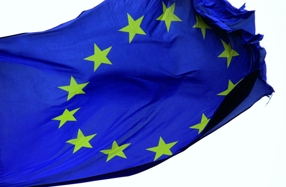 Die Flagge der Europäischen Union (ein Kreis gelber Sterne auf dunkelblauem Grund) flattert im Wind, sie ist an den Ecken schon ein wenig ausgefranst.