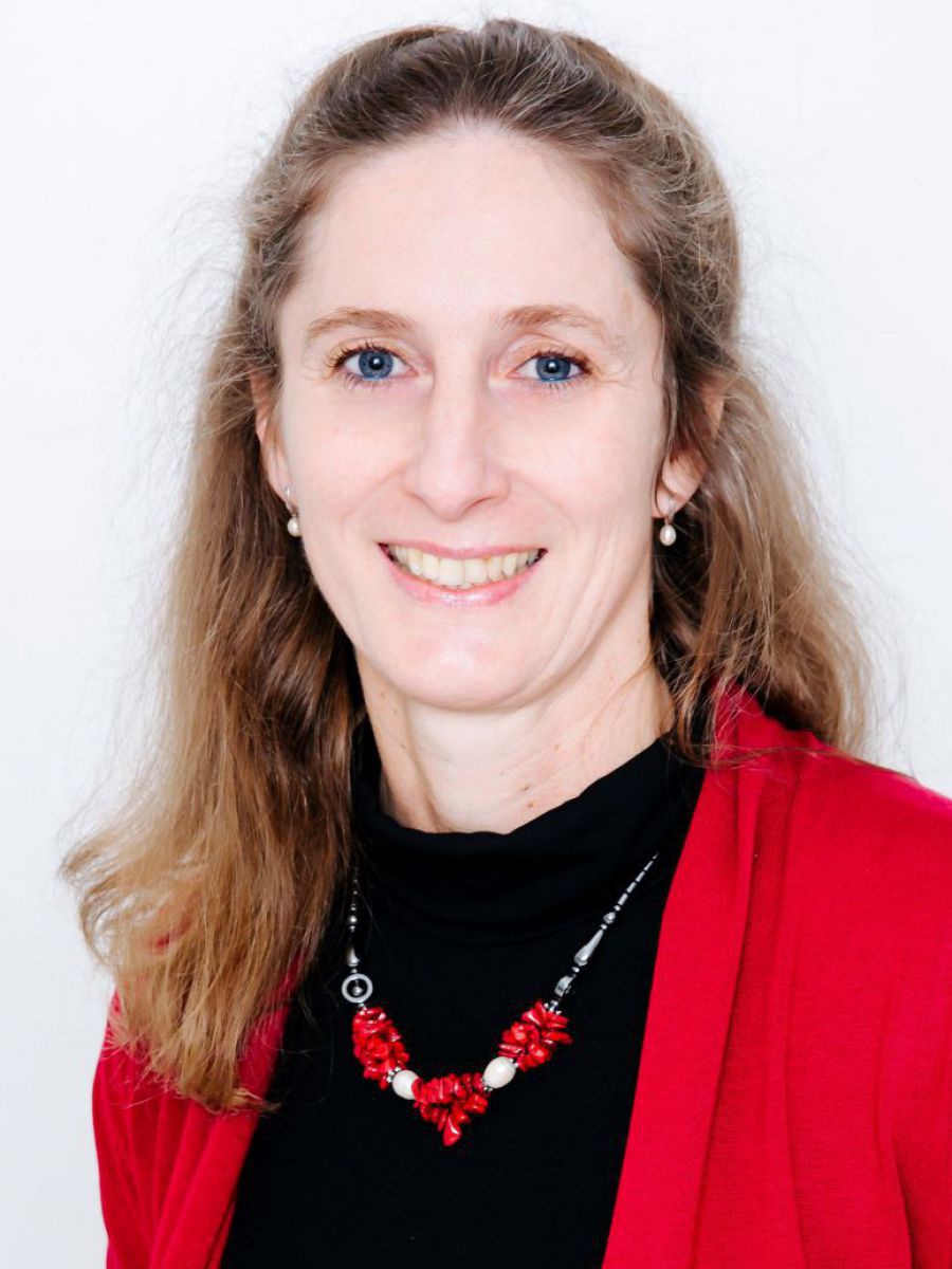 Lehrerin und Unternehmerin Karin Stummvoll hat langes naturblondes Haar, das sie zum Teil nach hinten frisiert hat. Ihre blauen Augen blicken offen in die Kamera, beim Lächeln zeigt sie weiße Zähne. Passend zu ihrem schwarzen Oberteil mit roter, offener W