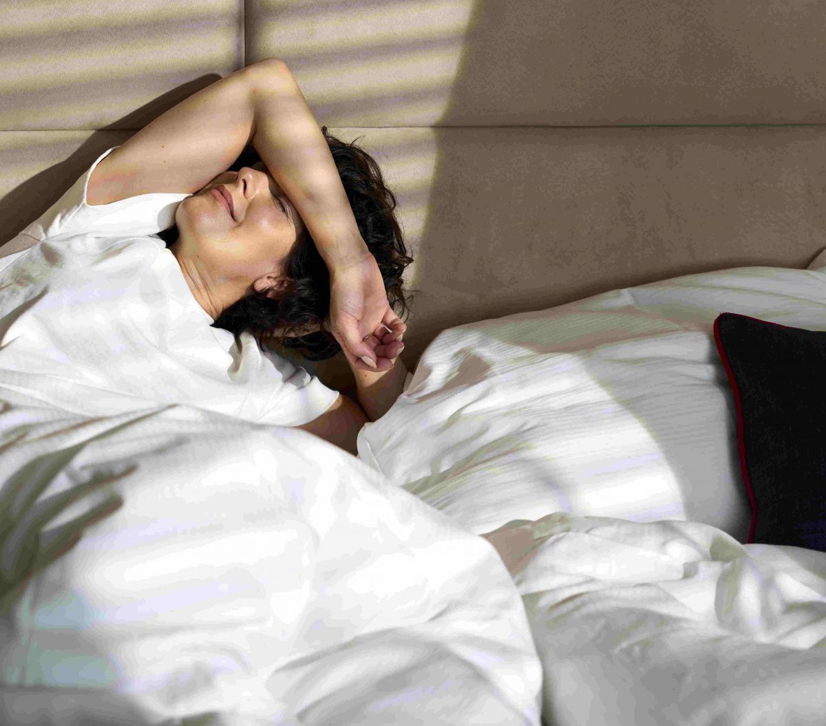 Eine junge Frau reckelt sich in einem Bett