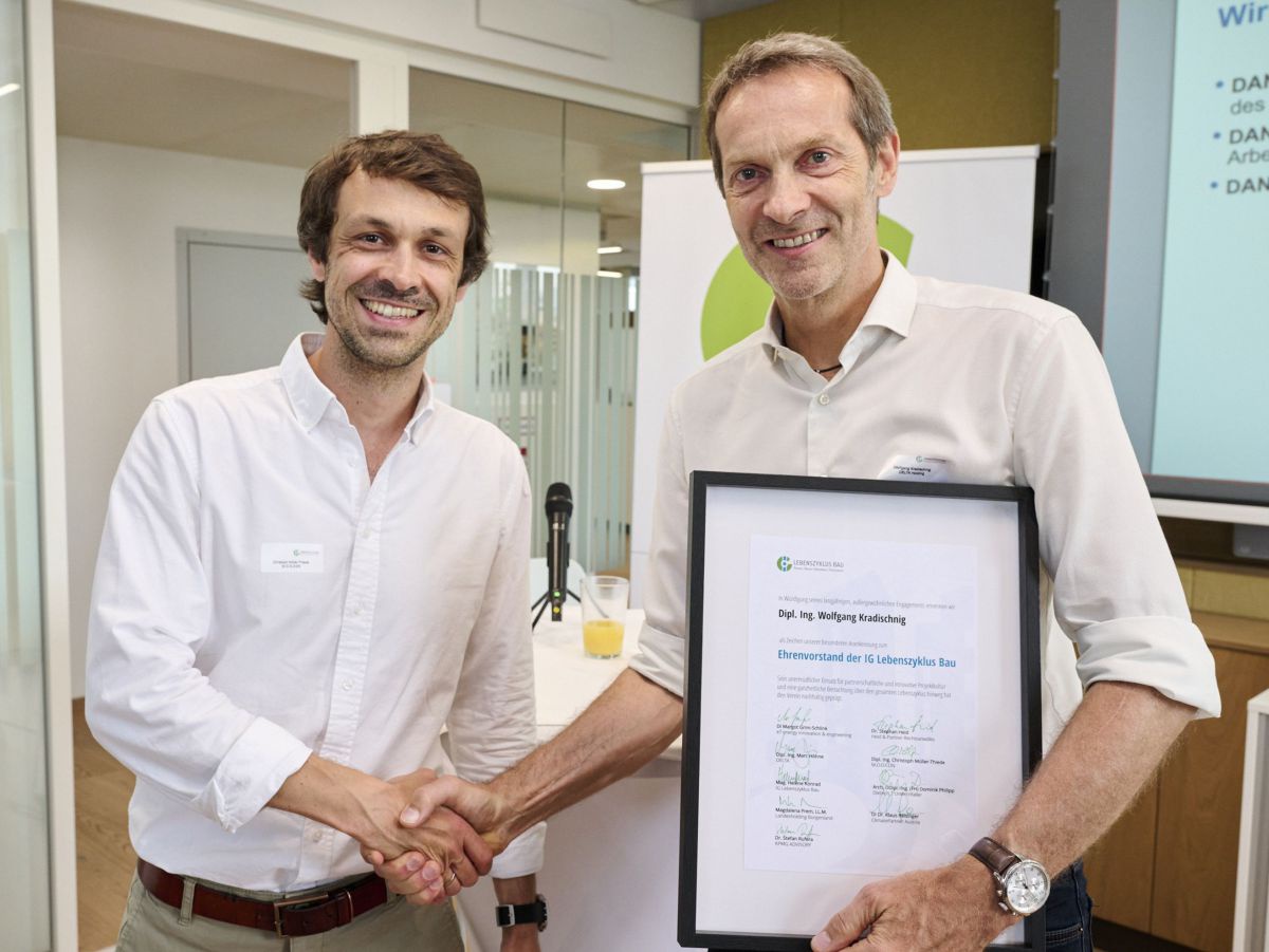 2 Männer geben sich einen Handschlag: Links Christoph Müller-Thiede, M.O.O.CON, rechts Wolfgang Kradischnig, DELTA - er hält die gerahmte Urkunde ins Bild. Beide lächeln.