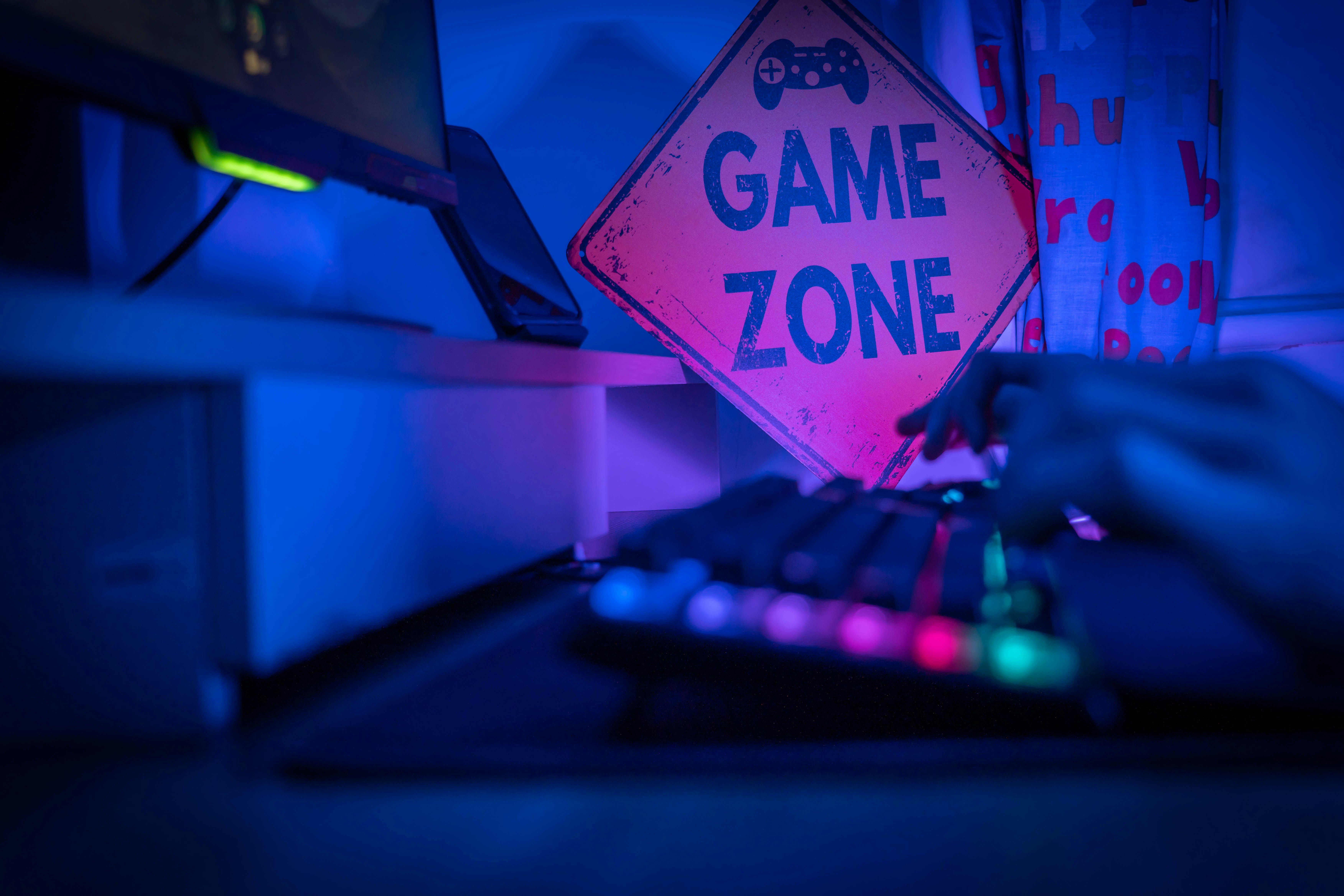 Tastatur zum Computerspielen, im Hintergrund ist ein Schild auf dem Game Zone steht,
