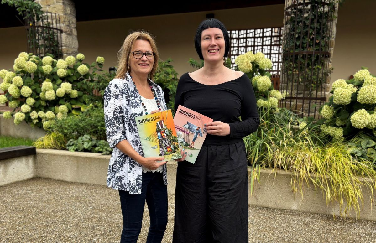 Roswitha Reisinger und Martina Madner stehen in einem Garten. Sie halten zwei Ausgaben der BUSINESSART in der Hand.
