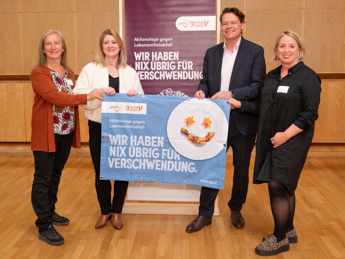 Vier Personen halten gemeinsam ein Plakat mit der Aufschrift: 