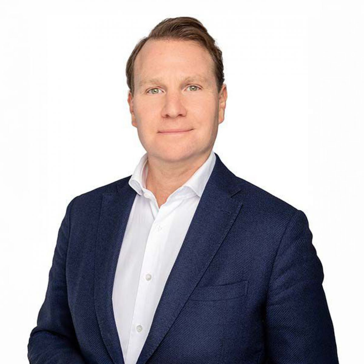 Portraitfoto von Thomas Krautschneider: Ein Mann mittleren Alters mit hellen Augen und dunkelblonder Haartolle, er trägt dunkelblaues Sakko über weißem Hemd.