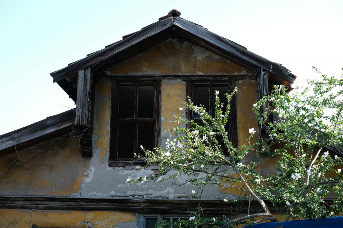 Ausschnitt von 2 Dachfenstern unter dem Giebel eines stark renovierungsbedürftigen Hauses. 