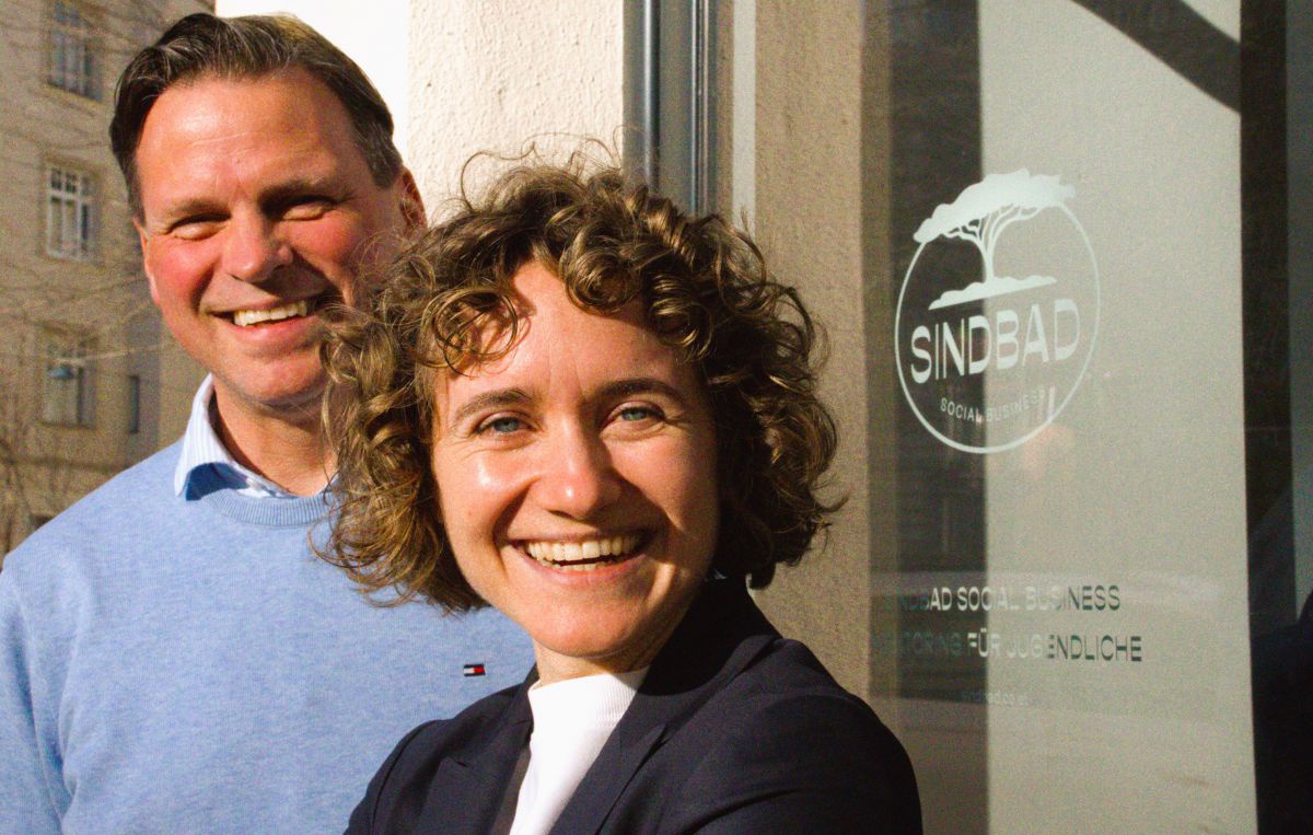 Nora Eberharter-Rhomberg und Bernd Hartweger, die neue Führung des Sozialunternehmens Sindbad sind vor der Glas-Eingangstüre des Unternehmens mit dem Logo darauf zu sehen. 