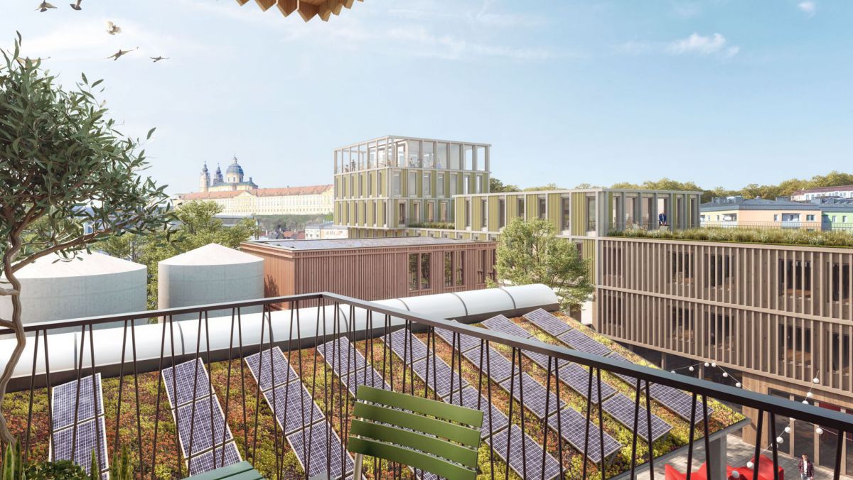 Visualisierung des geplanten Umbaus des Quartiers Tischlerei Melk: Blick von einem Balkon auf ein begrüntes Dach mit Photovoltaikanlage, dahinter weitere Gebäude mit Lichtschutz aus lamellenartigen Holzvorbauten. Im Hof unten sieht man bunte Sitzgelegenhe