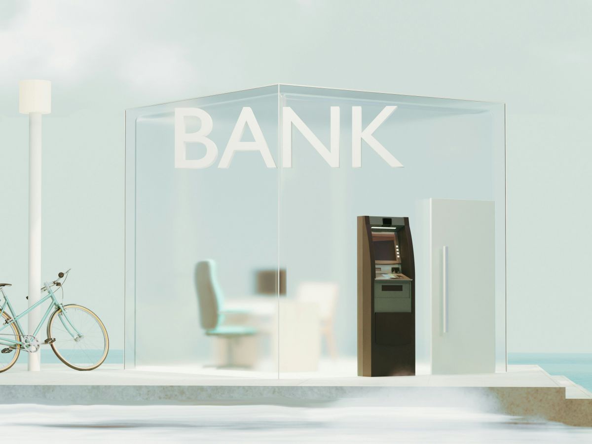 symbolbild für die innovationsbank: mit einem Bankomaten, einer Glaskabine, aus der ein Schreibtisch und Sessel und Computer durchscheinen. 