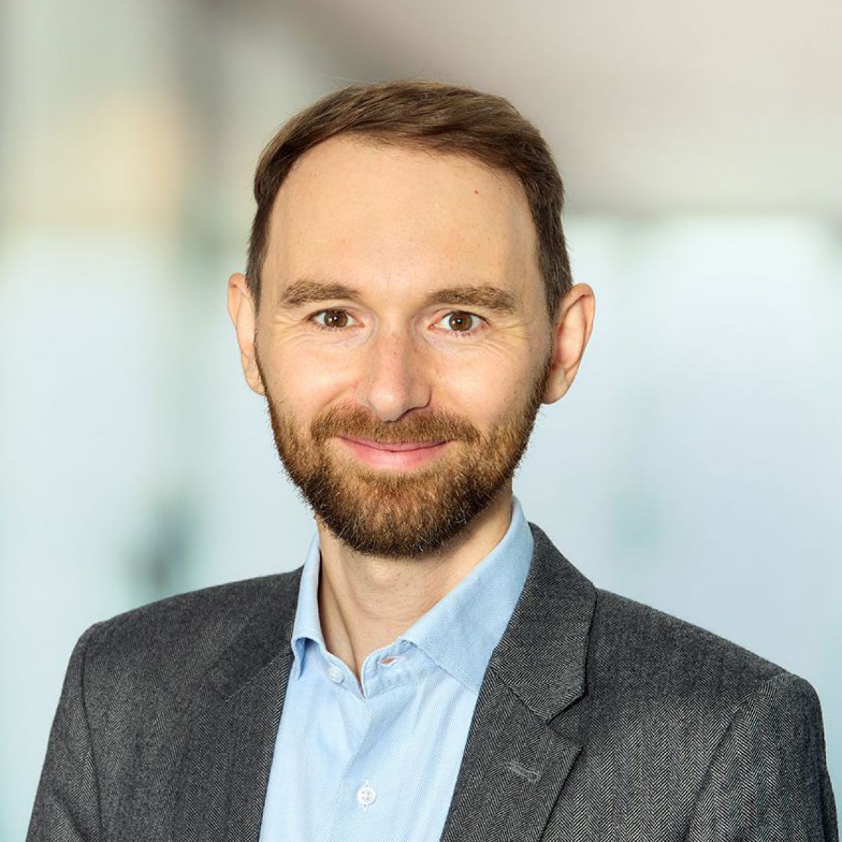 Matthias Haberl: Schlanker, bärtiger Mann, freundlich lächelnd, im grauen Sakko über hellblauem Hemd ohne Krawatte und offenen Kragen.