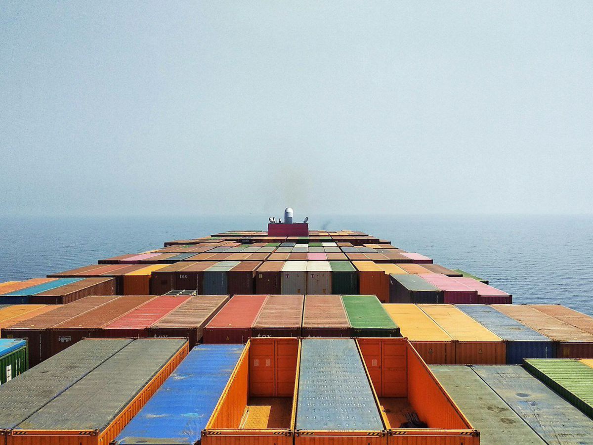 Blick auf ein riesiges Frachtschiff mitten auf dem Ozean. einige der bunten Container sind leer.