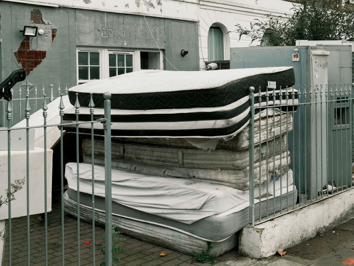 Ein Stapel alter Matratzen vor einem Gebäude.