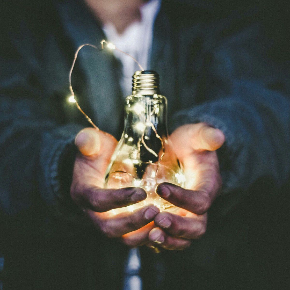 Mensch mit einer Glühbirne in der Hand als Symbol für Energie und Innovation