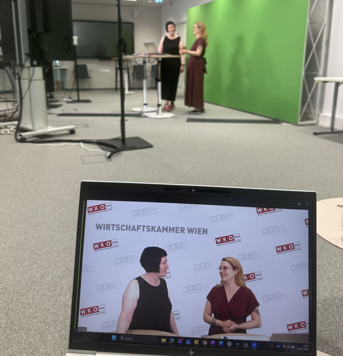 2 Frauen im Gespräch vor einem Green Screen. Im Vordergrund ein Bildschirm auf dem die beiden nochmals zu sehen sind.