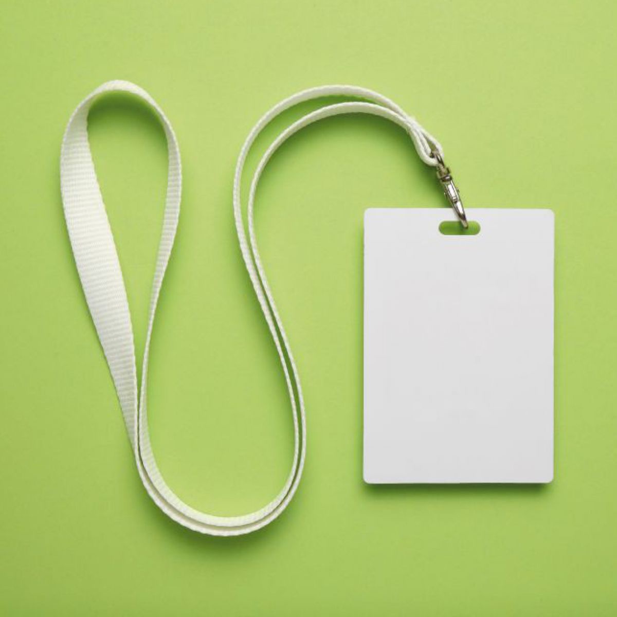 Ein weißes, leeres Badge an einem weißen Lanyard liegt auf grünem Hintergrund.