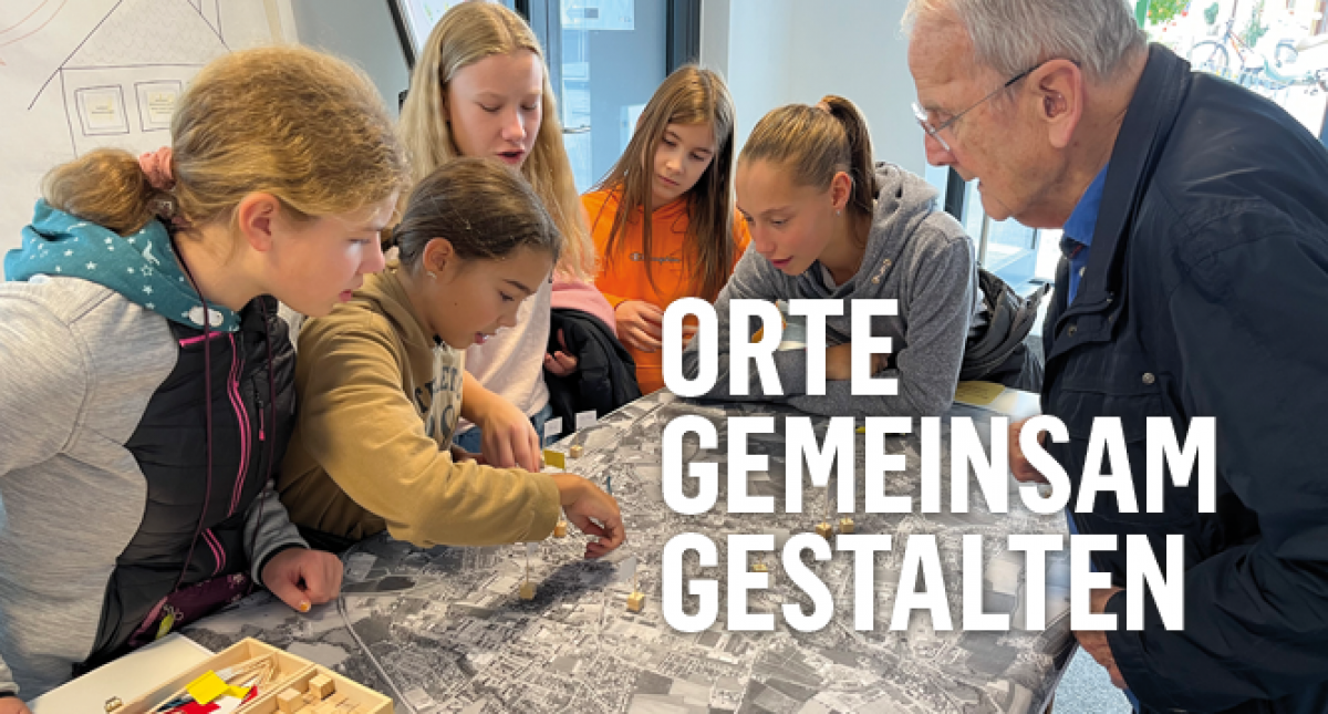 Das Titelbild zeigt einen älteren Herrn mit einer Gruppe von Mädchen im Mittelschulalter, die sich gemeinsam im Gespräch über ein Modell der Stadt beugen. Ein Mädchen zeigt gerade auf einen Punkt auf dem Plan.