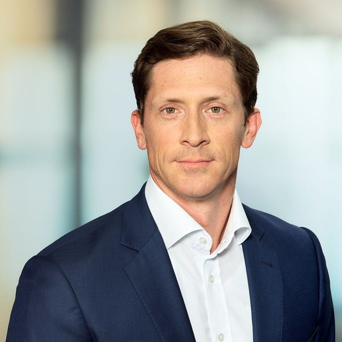 Portraitbild von Philipp Schöckler: Mann in seinen Vierzigern mit hellbraunem, leicht gewelltem Kurzhaarschnitt in weißem Hemd ohne Krawatte und blauem Sakko.