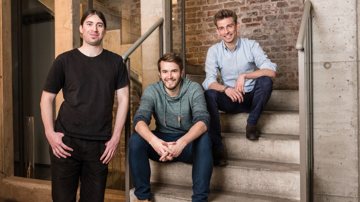 Das refurbed team: zwei sitzen auf einer Stiege, einer steht daneben