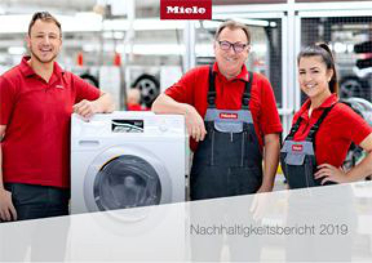 Miele-Mitarbeiter*innen stehen rund um eine Waschmaschine