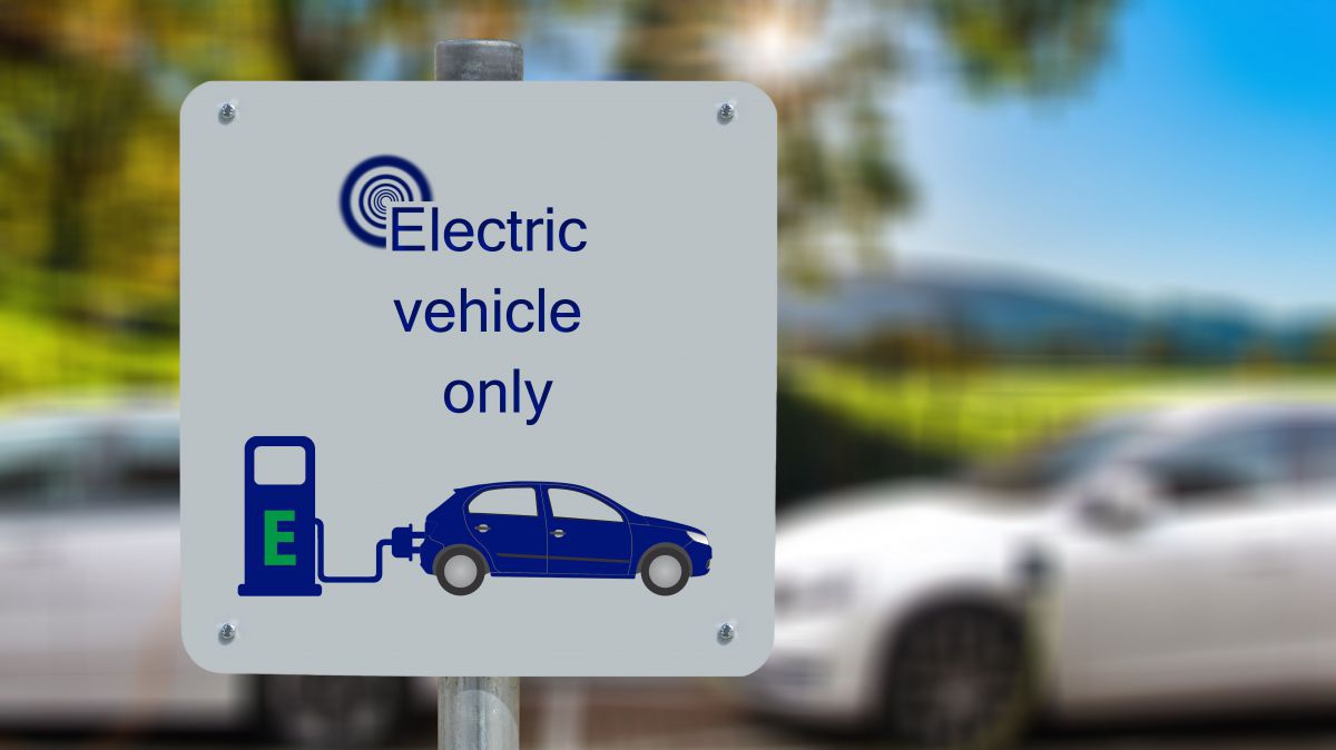 Ein Schild mit dem Piktogramm eines Elektroautos, das gerade an eine E-Zapfsäule angeschlossen ist. Darüber steht geschrieben: 