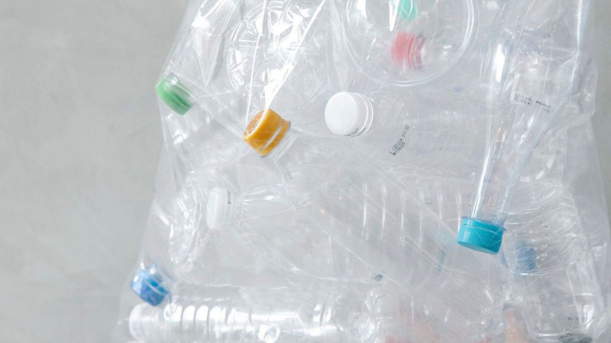 Verschiedene Plastikflaschen mit färbigen Verschlüssen in einem transparenten Müllsack.