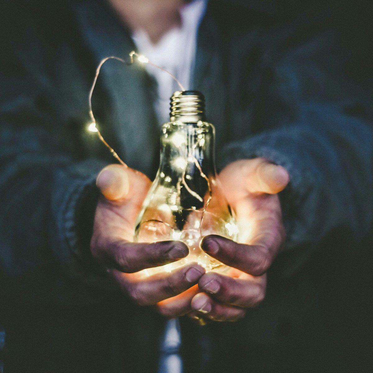 Mensch mit einer Glühbirne in der Hand als Symbol für Energie und Innovation